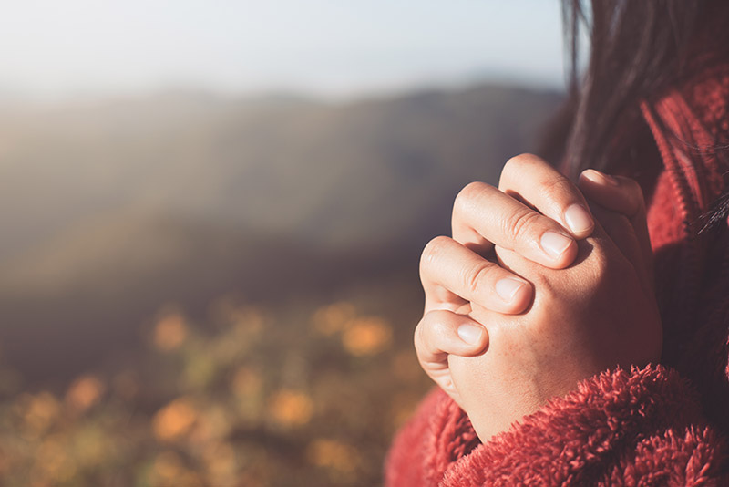 A woman's hands clasped in prayer