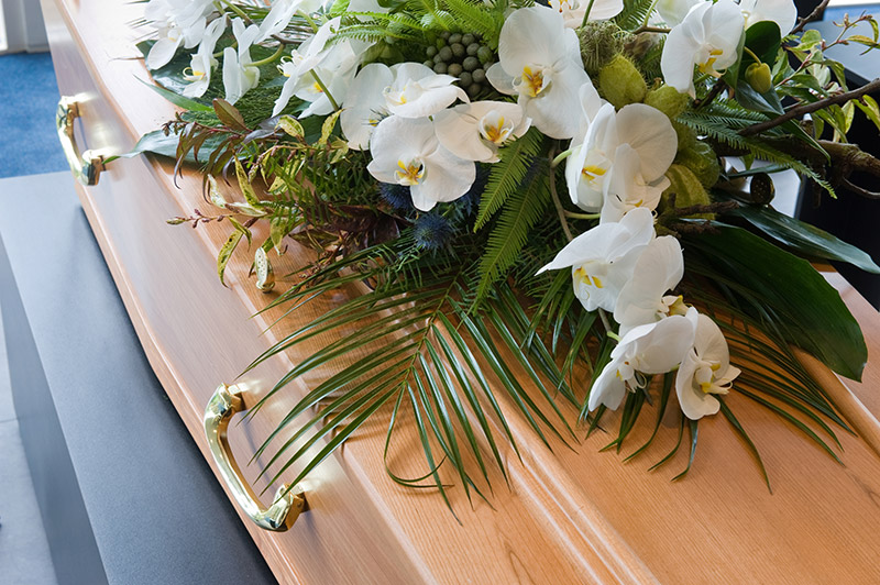 A casket with an arrangement of white flowers on top